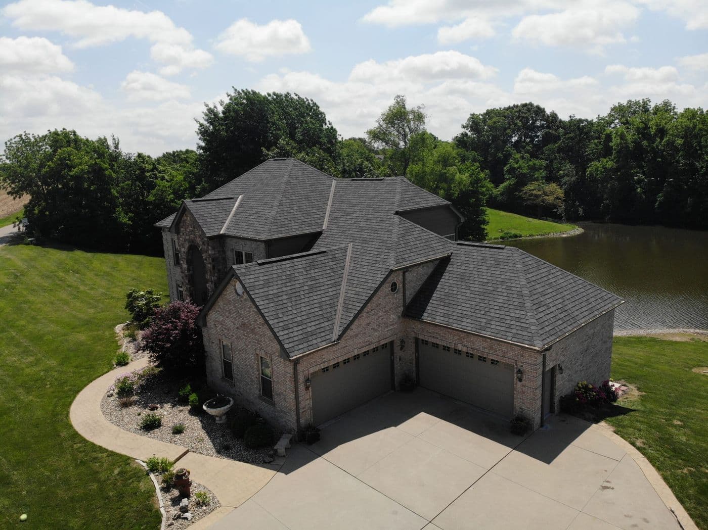 Aerial view of a completed brick home re-roof beside a lake