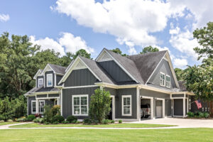 A large gray craftsman new construction house with a landscaped yard