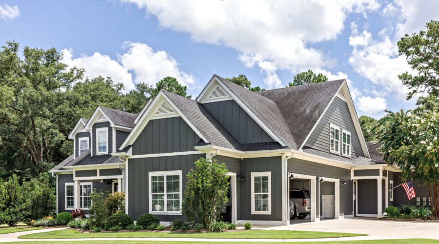 A large gray craftsman new construction house with a landscaped yard